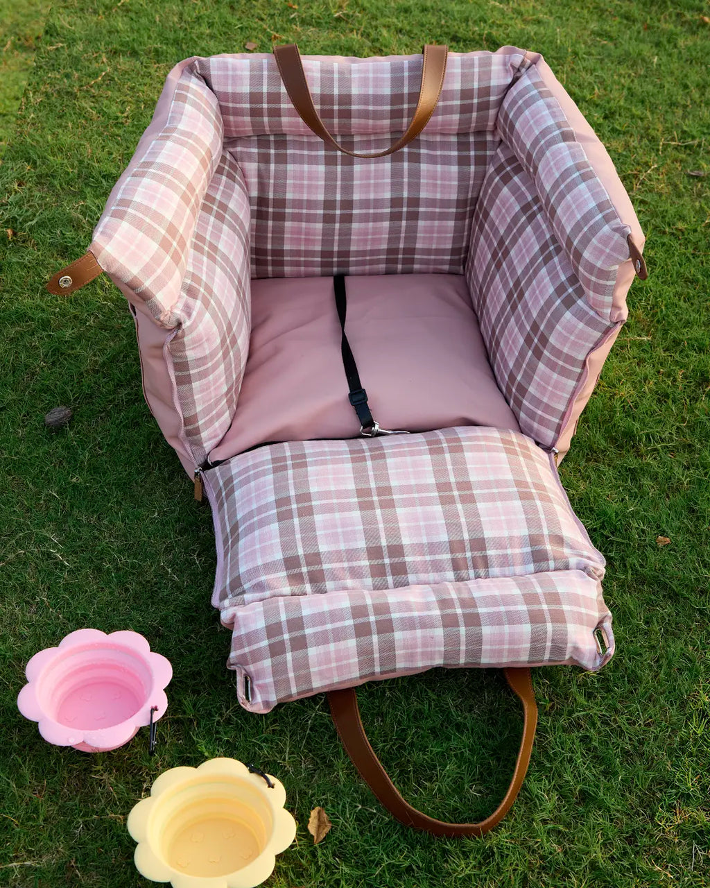 Front view of pink plaid dog car booster seat with safety harness clip