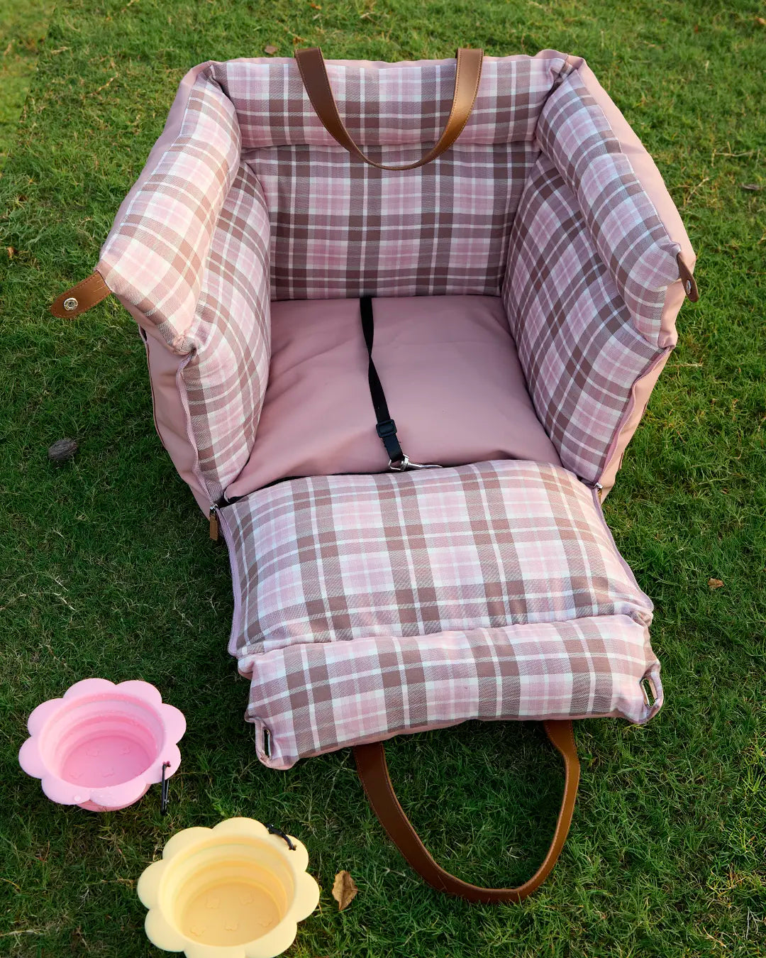 Front view of pink plaid dog car booster seat with safety harness clip