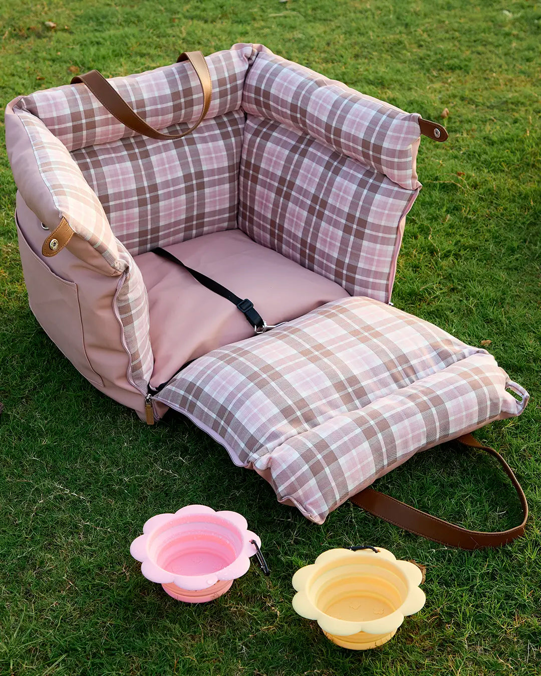 Pink plaid dog car booster seat with safety leash on the grass