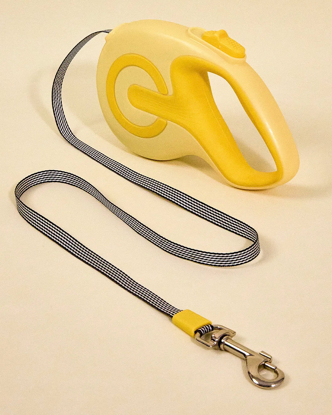 Yellow retractable dog leash with the nylon cord fully extended, shown on a plain background