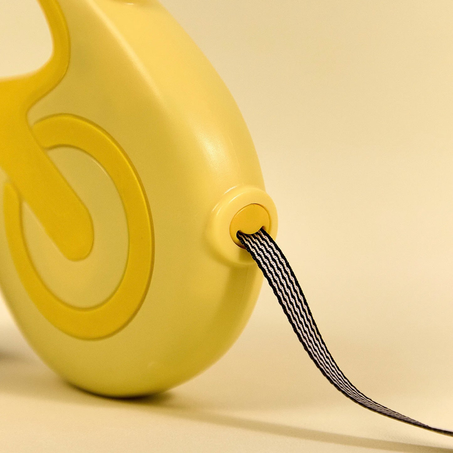 Close-up of the ergonomic handle and reel on a yellow Charpaw retractable dog leash