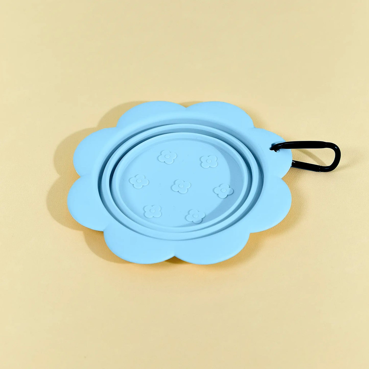 Blue collapsible flower pet bowl shown open with a carabiner clip attached