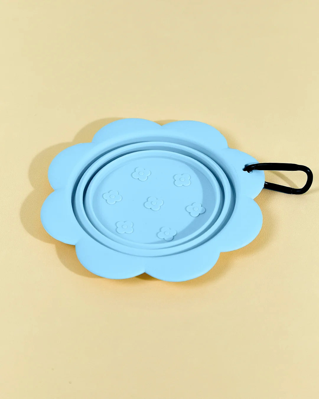 Blue collapsible flower pet bowl shown open with a carabiner clip attached