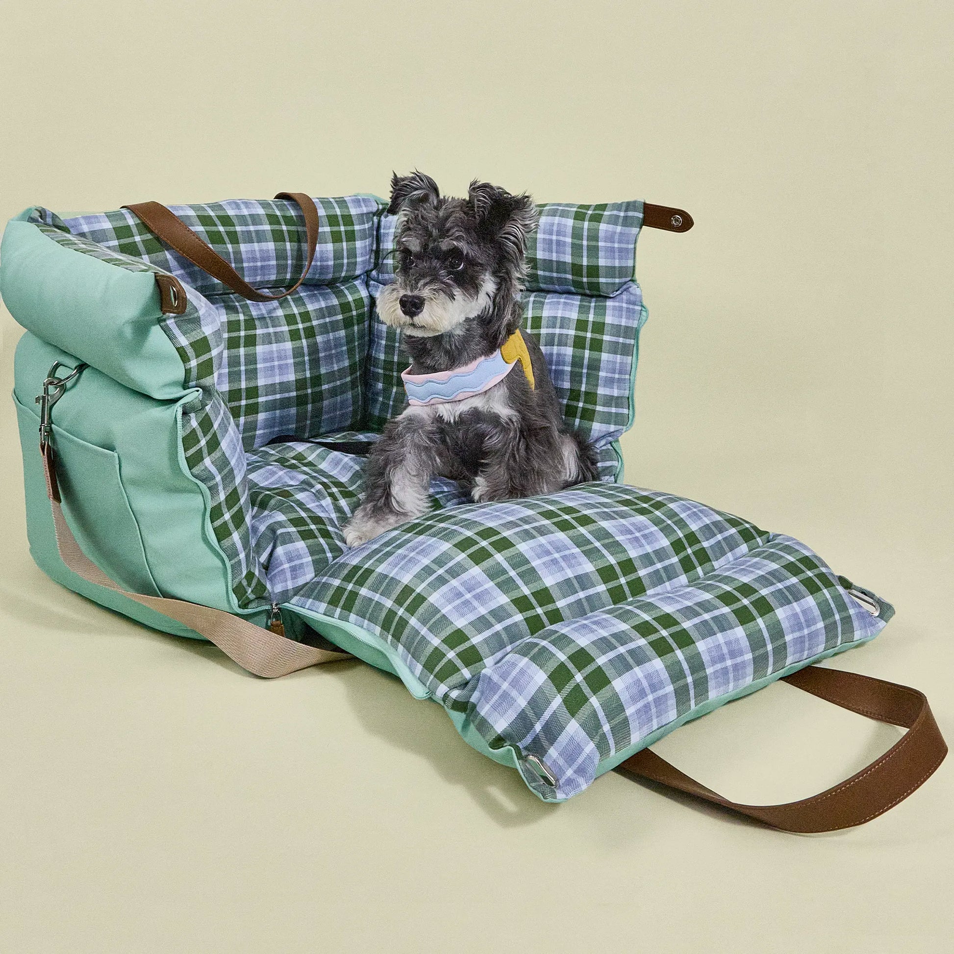 Green plaid dog booster seat unzipped at the front to create an open pet lounge sofa, providing outdoor travel comfort for dogs or cats.