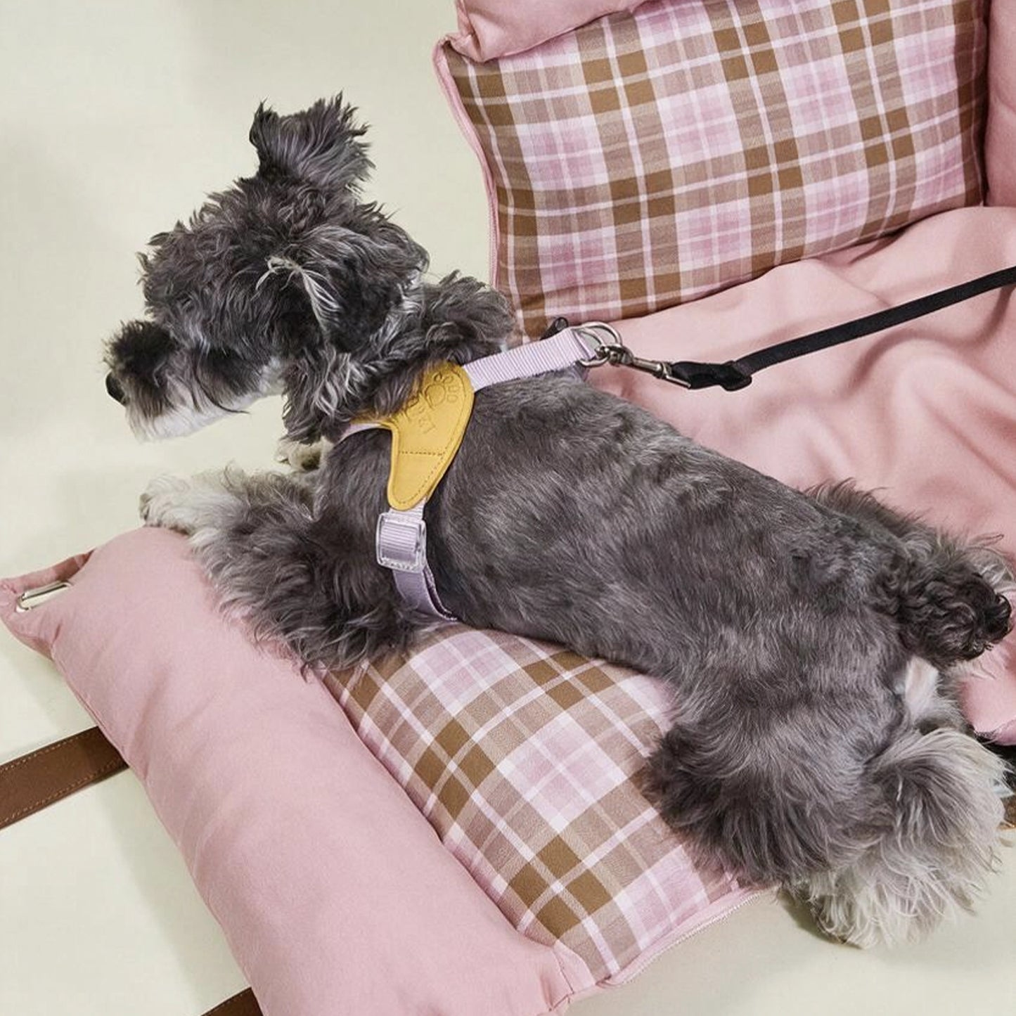 Pink plaid dog car seat with the front panel unzipped and expanded, transforming from a secure car booster into a relaxing travel couch for dogs or small cats.