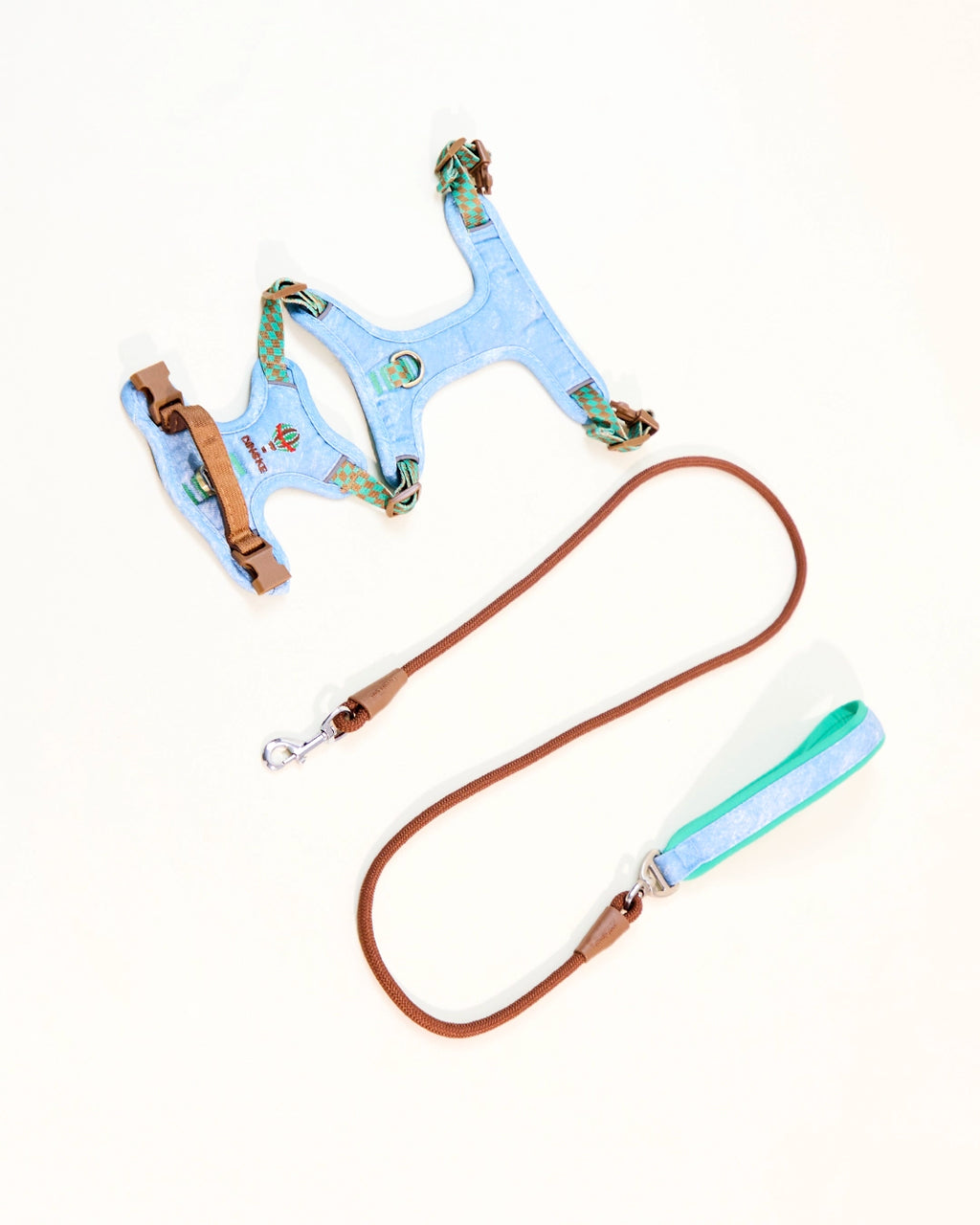 Light blue embroidered denim dog harness laid flat with leash