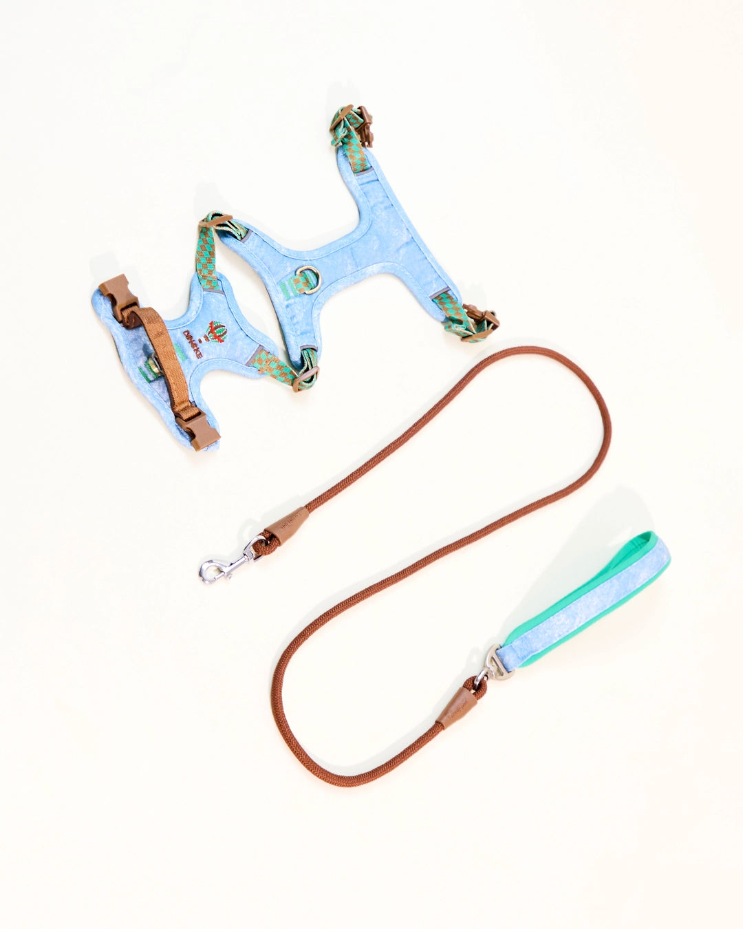 Light blue embroidered denim dog harness laid flat with leash