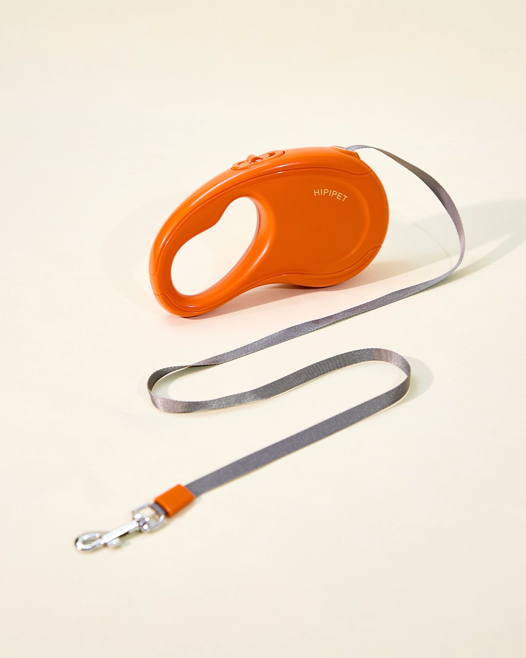 Orange retractable dog leash with extended grey tape leash